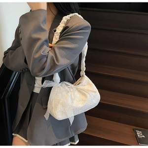 Detail of white lace tote bag featuring intricate floral patterns and a side bow knot