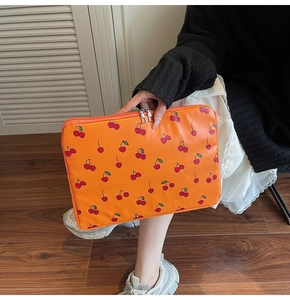 Détail de la housse d'ordinateur orange à motif cerises avec double fermeture éclair