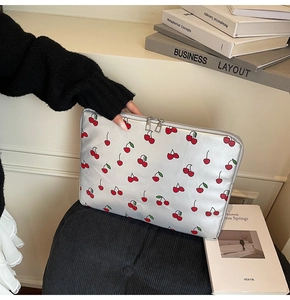 Gros plan d'une housse d'ordinateur argentée à motifs cerises et double fermeture