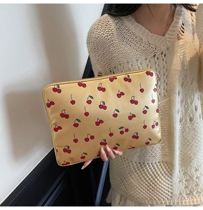 Détail de la pochette dorée à motif cerise avec aspect satiné et fermeture éclair