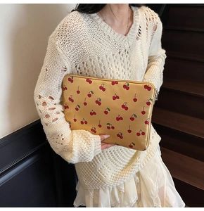 Détail de la pochette ordinateur effet soie avec imprimés cerises et fermeture éclair