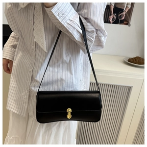 Close-up of elegant black underarm bag featuring a golden hardware twist-lock buckle on the flap