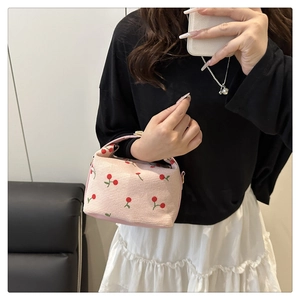 Detailed texture of pink corduroy handbag featuring cute red cherry embroidery patterns