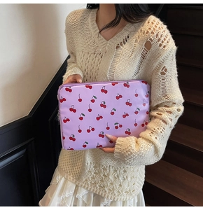 Close-up of lavender laptop sleeve featuring red cherry pattern held by a woman