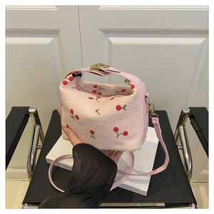 Detailed shot of pink cherry print handbag with gold buckle and adjustable strap