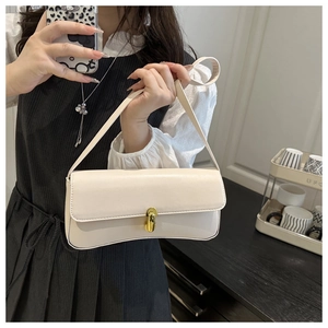 Detail of the golden metal buckle closure on a minimalist cream leather shoulder bag