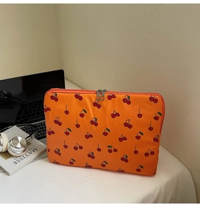 Détail de la housse d'ordinateur orange avec motif cerises et double fermeture éclair