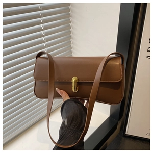 Detailed view of brown matte leather baguette bag with a sleek gold vertical metal clasp
