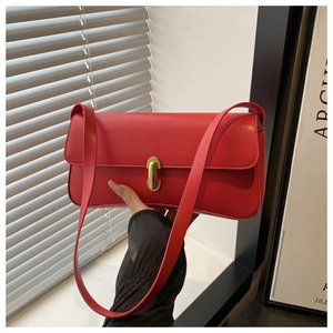 Close-up of minimalist red baguette bag with elegant gold twist-lock and matte finish