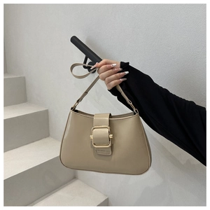 Dettaglio di una borsa a mano beige minimalista in pelle con fibbia dorata