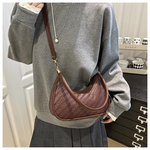 Detail of brown woven crescent bag showing intricate texture and adjustable leather strap