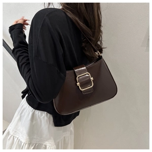 Dettaglio di borsa sottobraccio in pelle lucida marrone scuro con fibbia dorata