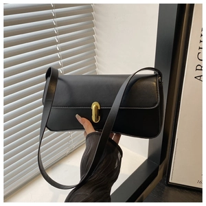 Detailed close-up of a black matte leather shoulder bag with a gold metal twist lock