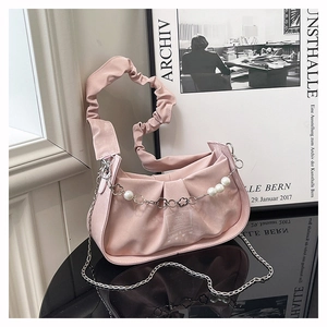 Detail of pink faux suede bag featuring pleated handle and white pearl floral chain