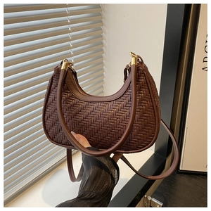 Close-up of the dark brown woven leather texture and golden zipper on the hobo bag