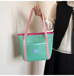 Detail of mint green mesh tote bag with pink handles and woven brand label