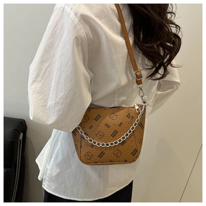 Detail of a brown leather bucket bag featuring cartoon bear print and metal chain strap