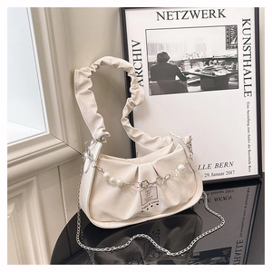 Close-up of pleated cream handbag featuring ruffle strap and decorative pearl floral chain