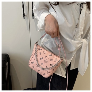 Close-up of pink bucket bag with bear patterns and silver chain strap on a model