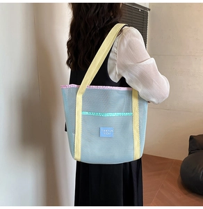 Close-up of mesh tote bag with blue netting and yellow straps on model shoulder