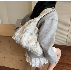 Detail of white furry tote bag with blue butterfly prints shown on model shoulder