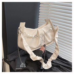 Detail of cream pleated underarm bag with pearl chain and metallic flower accents
