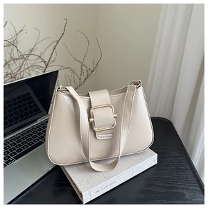 Dettaglio di una borsa a spalla beige in pelle con una grande fibbia in metallo dorato