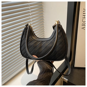 Close-up of black woven crescent bag featuring gold zipper and detachable shoulder strap