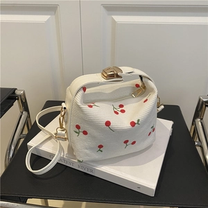 Off-white corduroy tote bag with cherry print and detachable shoulder strap on books