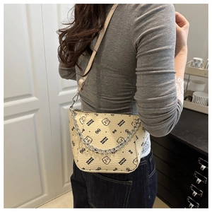 Detailed view of beige monogram bucket bag with chain strap worn by model