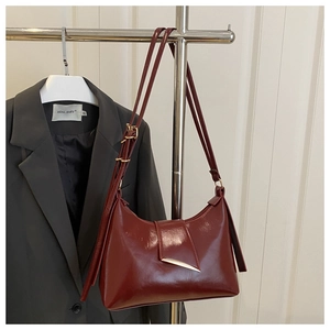 Detail of dark red glossy leather shoulder bag with golden metallic hook closure
