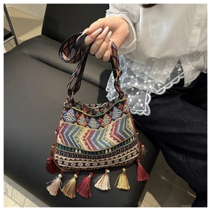 Close-up of ethnic style embroidery tote bag with colorful fringe tassels and woven strap
