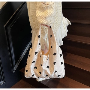 Chic beige tote bag with black heart patterns shown in a lifestyle staircase setting