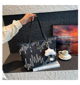 Detail of black embossed tote bag with white wave stitching and cloud plush charm