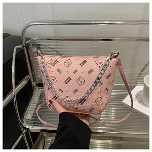 Close-up of pink bucket bag with litchi texture leather, metal chain and cartoon print