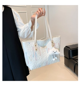 Detail of white quilted tote bag with colorful embroidery and cloud charm accessory