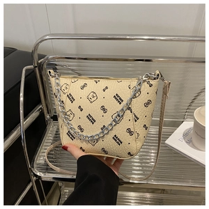 Close-up of cream textured leather bucket bag with bear print and silver chain detail