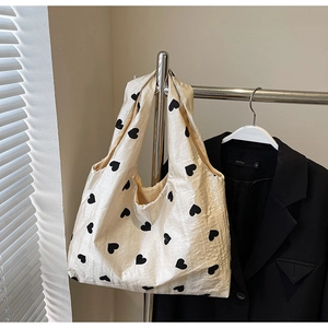 Close-up of cream fabric tote bag with black heart patterns and textured surface