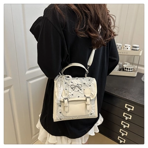 Detail of off-white bow mini backpack with lace embroidery and pearl chain accents
