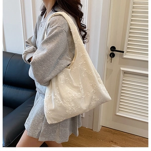 Détail de broderie florale en mousseline blanche sur un grand sac cabas souple