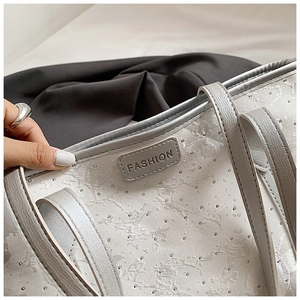 Detail of silver-grey tote bag showing cloud pattern fabric and rhinestone accents