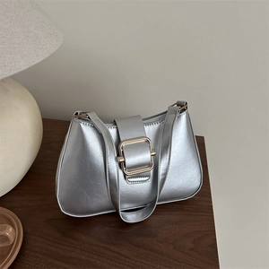 Borsa sottobraccio argento metallizzato con fibbia dorata su sfondo in legno materico