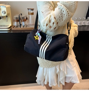 Detail of black sports duffel bag with three white stripes and creative star pendant