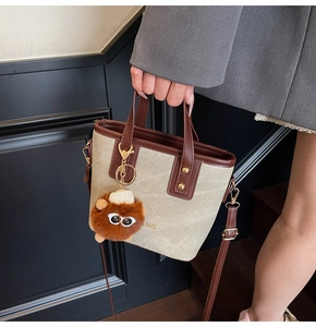 Vue détaillée du sac cabas en toile beige avec finitions en cuir brun et breloque