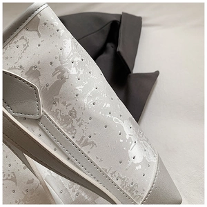 Macro detail of silver metallic texture and rivet craftsmanship on pointed-toe shoes