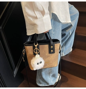 Détail du sac seau marron avec charm en peluche et logo mode sur bandoulière