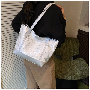Detail of white butterfly print and silver fashion emblem on large tote bag