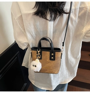 Détail du sac seau bandoulière texture sable marron avec breloque boule en peluche