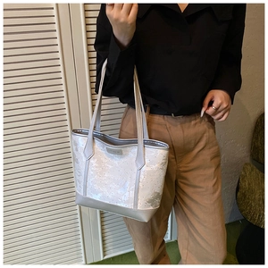 Detail of silver tote bag with gray abstract patterns and silver Fashion metal logo
