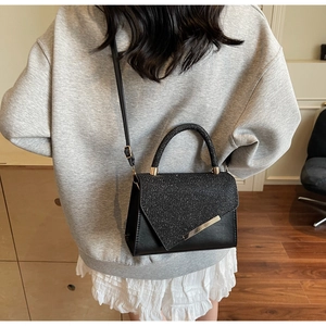 Detail of a chic black leather crossbody bag with sparkling rhinestones and metal accents